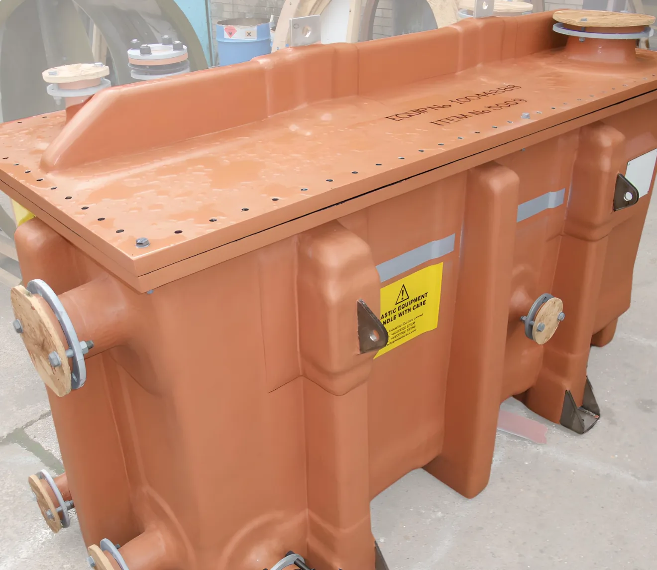 Rectangular industrial containment tank with flanged pipe connections inside a workshop